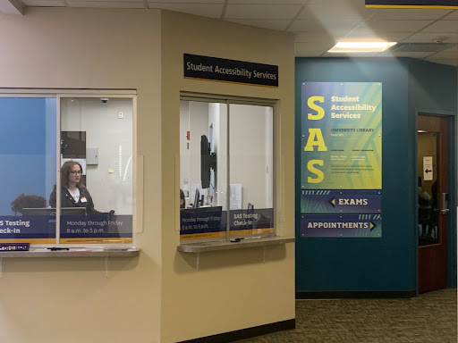 Photo shows the service window of the SAS office on the first floor of the LIbrary, where an employee is working.